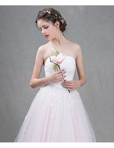 a woman in a white dress holding a flower and wearing a pink tulle skirt