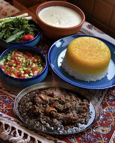 a table topped with plates and bowls filled with food next to rice, meat and vegetables