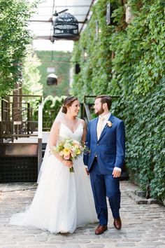 a bride and groom standing together in front of greenery