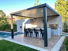 an outdoor kitchen with bar stools next to a pool