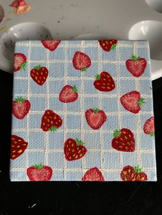 a cloth with strawberries on it is sitting next to a white plate and spoon