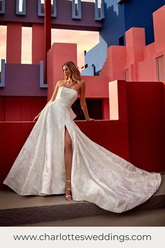 a woman in a white wedding dress posing for a photo with red and blue buildings behind her