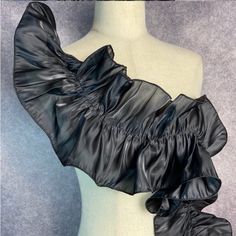 a mannequin wearing a black leather dress with ruffles on the shoulders