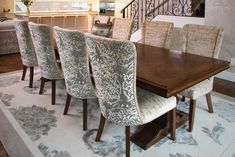 the dining room table is set with upholstered chairs and an area rug on the floor