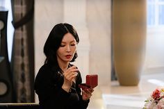 a woman sitting at a table holding a piece of chocolate