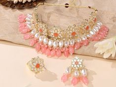 This elegant kundan choker necklace set is a perfect addition to any traditional or fusion outfit. The choker is adorned with sparkling kundan stones and accented with pearl drops for added glamour.  The necklace is made of high-quality alloy and is gold plated for durability. It's perfect for special occasions such as weddings, festivals, and parties. Make a statement with this beautiful necklace set. Necklace lenght : 47cm Earring lenght     : 6cm Ring size               :2 cm ( adjustable ) Kundan Choker Set, Unique Wedding Jewelry, Jewelry Kundan, Kundan Jewelry, Kundan Choker, Choker Jewelry, Choker Necklace Set, Choker Set, Bridal Jewellery Indian