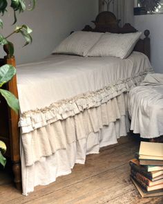 a bed sitting next to a pile of books on top of a wooden floor