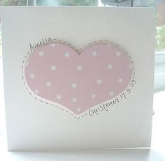 a card with a pink heart and white polka dots on the front, in an open window sill