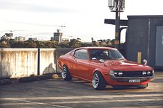 an orange muscle car parked in a parking lot