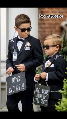 two young boys dressed in suits and holding signs