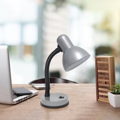 an open laptop computer sitting on top of a wooden table next to a desk lamp