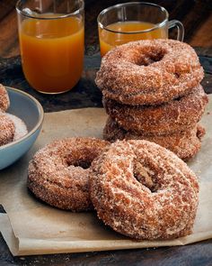 some sugared donuts are on a table next to orange juice