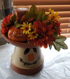 an arrangement of flowers and pumpkins in a decorative vase with the words give thanks written on it