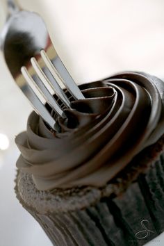 a cupcake with chocolate frosting and a fork stuck in it