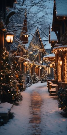 a snowy street lined with lit up christmas trees and houses covered in snow at night