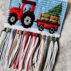 a cross stitch christmas ornament with a red truck and tree on the front