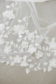 white flowers and leaves are on the sheered fabric that is laying on the floor