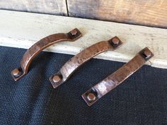 two metal handles sitting on top of a black mat next to a wooden door frame