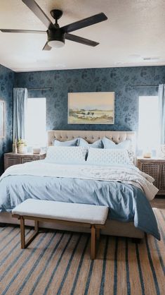 a bedroom with blue walls and carpeted flooring has a large bed in the middle