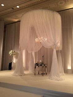 a white wedding setup with drapes and chandelier