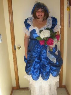 a woman in blue and white dress standing next to a door with flowers on it