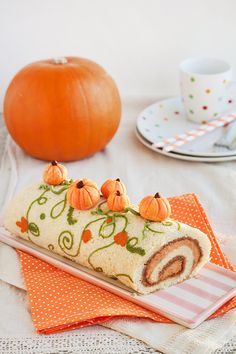 a roll with pumpkins on it sitting next to a cup and saucer in the background