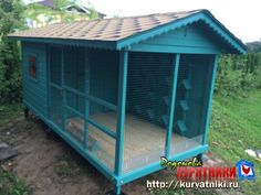 a small blue chicken coop sitting on top of a grass covered field