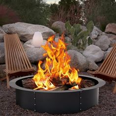 a fire pit sitting in the middle of a gravel field next to some chairs and rocks