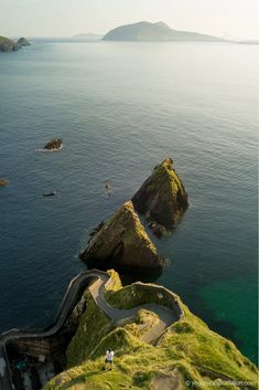 an aerial view of the ocean with people walking on it and cliffs in the background