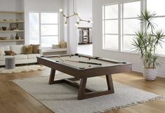 a pool table in the middle of a living room with white walls and wood floors