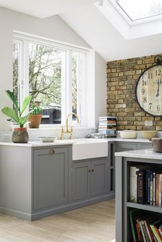 a kitchen with a large clock mounted to the wall next to a sink and bookshelf