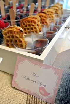 some waffles and berries are on display in a white tray with a name tag