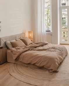 a large bed sitting in a bedroom on top of a wooden floor next to a window