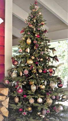 a decorated christmas tree in front of a red brick wall with ornaments hanging from it