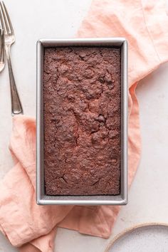 a square pan filled with brownies next to a fork and napkin on top of a table