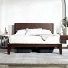 a bed sitting on top of a white rug next to a wooden headboard and foot board