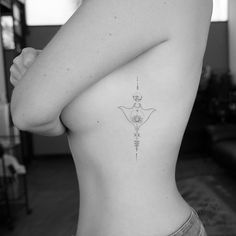 a woman's back with a tattoo on her left side and an arrow in the middle