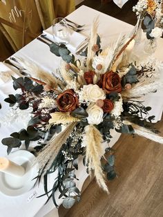 an arrangement of flowers on a table at a wedding reception with candles and napkins