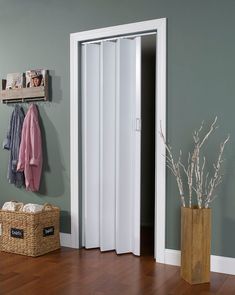 an open door in the corner of a room with a basket and coat rack next to it