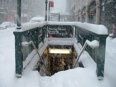 there is a bench covered in snow on the street