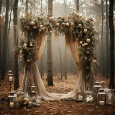 an outdoor wedding arch with flowers and candles in the woods on a foggy day