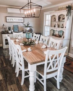 a dining room table with white chairs and a wooden centerpiece on top of it