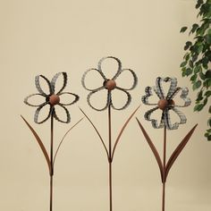 three metal flower sculptures sitting on top of a table