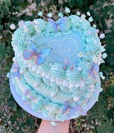 a heart shaped blue cake with butterflies on it's top and the number twenty