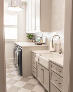 a kitchen with white cabinets and checkered flooring on the floor, along with a washer and dryer