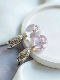 three purple flowers are hanging from the side of a white plate on top of a table