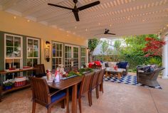 an outdoor dining area with table, chairs and couches under a covered patio ceiling