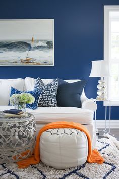 a living room with blue walls, white couches and pillows on the rugs