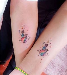 two girls with matching tattoos on their arms, one is holding the other's arm