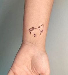 a small tattoo on the wrist of a woman's left hand with a dog head